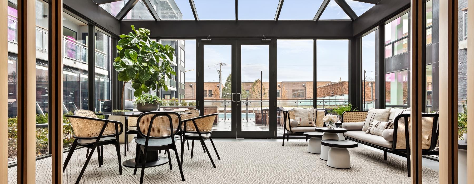 a room with a table chairs and a large window with a view of a city